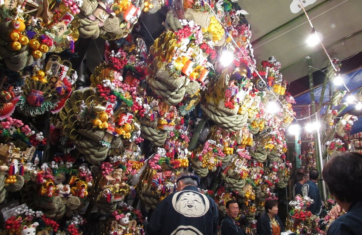Dicht behängter Kumade-Stand mit bunten Glücksrechen auf einem Tori-no-Ichi-Markt in Japan
