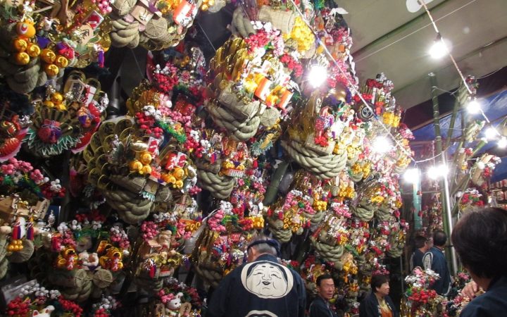 Dicht behängter Kumade-Stand mit bunten Glücksrechen auf einem Tori-no-Ichi-Markt in Japan